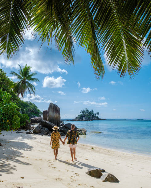 Mahe Seychelles, tropical beach with palm trees and a blue ocean at Mahe Seychelles Anse Royale beach, couple man and woman on vacation Seychelles stock photo
