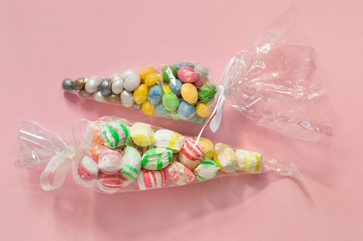 Colorful marshmallow and dragee candies wrapped in plastic on pink background