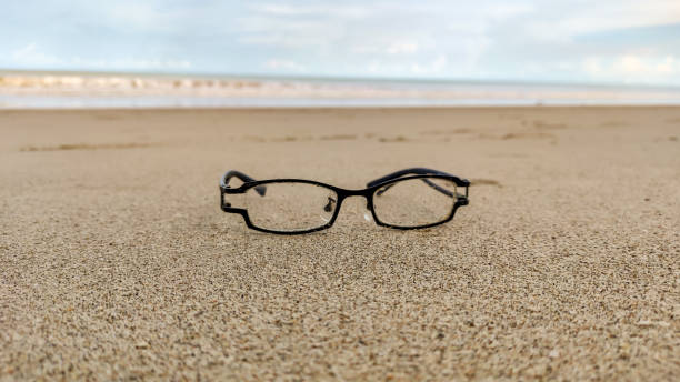 istock Black framed glasses lay on the sand at the beach. 1407984152