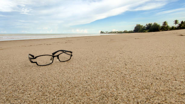 istock Black framed glasses lay on the sand at the beach. 1407984154