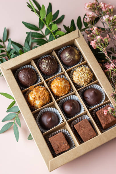 istock Gift craft box with assorted chocolates and pink flowers on a pink background. 1407985471