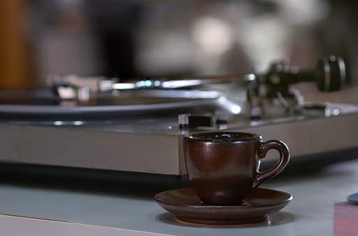 A cup or mug of Espresso or Ristretto Shot of Coffee with a blur background of Vinyl Record Longplay Player