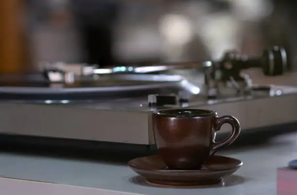 Photo of A cup or mug of Espresso or Ristretto Shot of Coffee with a blur background of Vinyl Record Longplay Player