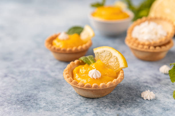 istock Mini tarts with lemon curd, mini meringue, lemon slices and mint, blue concrete background. 1407985555