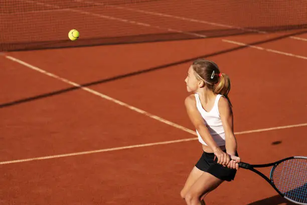 Active tennis player returning tennisball with her racket on a clay court. Sport and healthy lifestyle concept