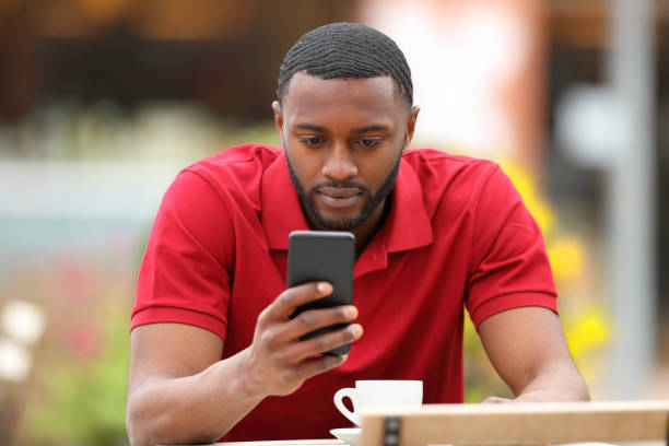 istock Serious black man using cell phone in a bar terrace 1407985862