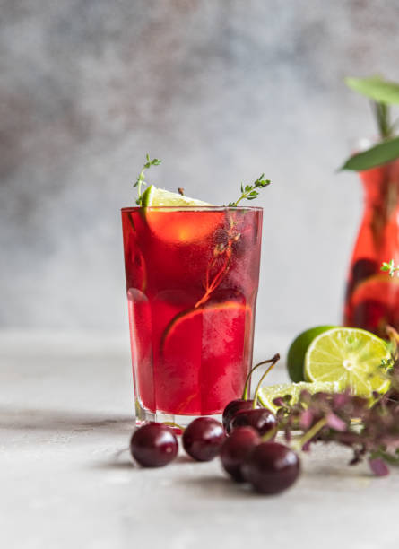 istock Cocktail or lemonade with cherries and lime, grey background. Mocktail. Cold summer drink. 1407985927