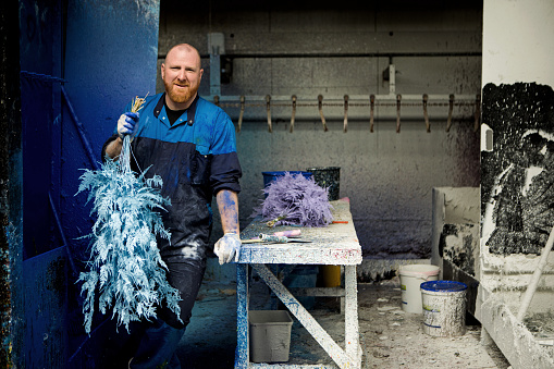 A redhead male worker on an flower painting production line in a facility in Holland