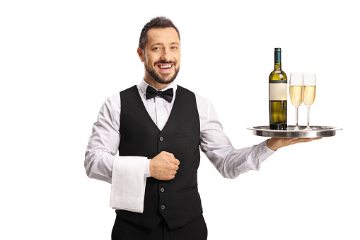 Smiling waiter holding bottle of wine and glasses on a tray isolated on white background