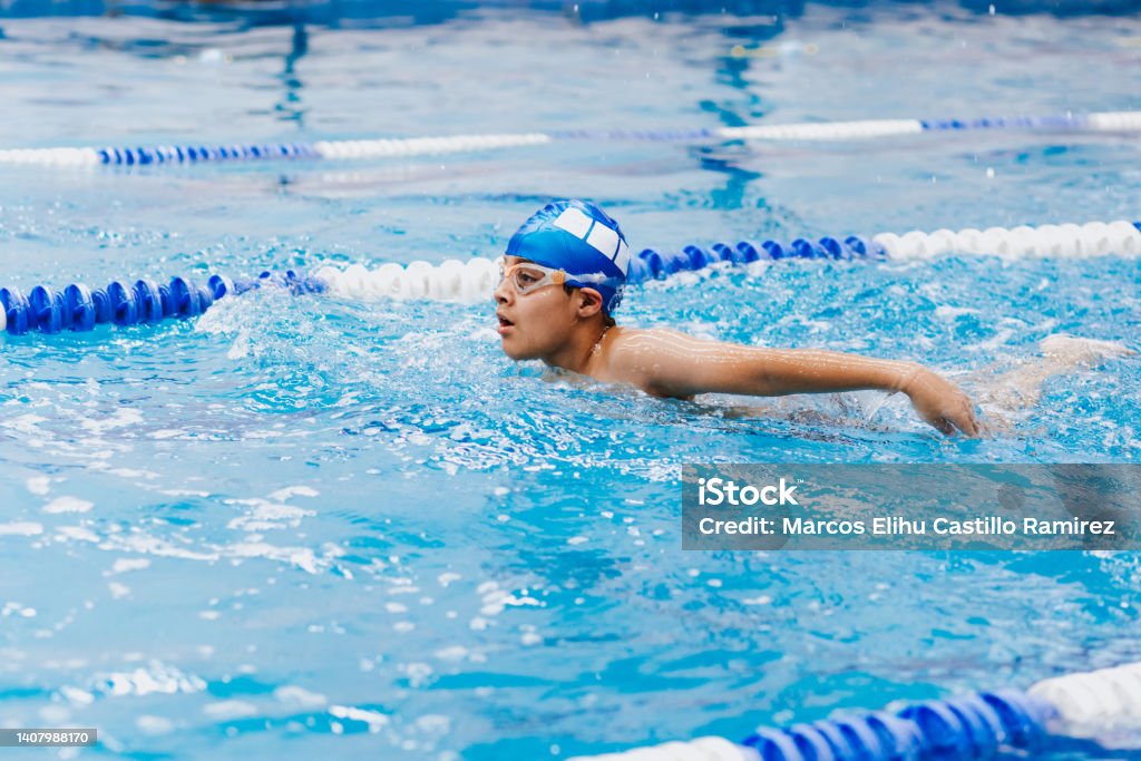 latin child boy swimmer wearing cap and goggles in a swimming training at the Pool in Mexico Latin America Swimming Stock Photo
