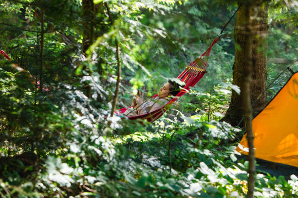 woman laying down in hammock reading book copy space