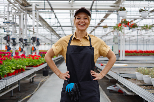 Happy woman florist in greenhouse