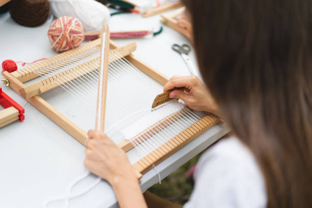 istock Girl weaving small rug with pattern at masterclass on weaving 1407990239