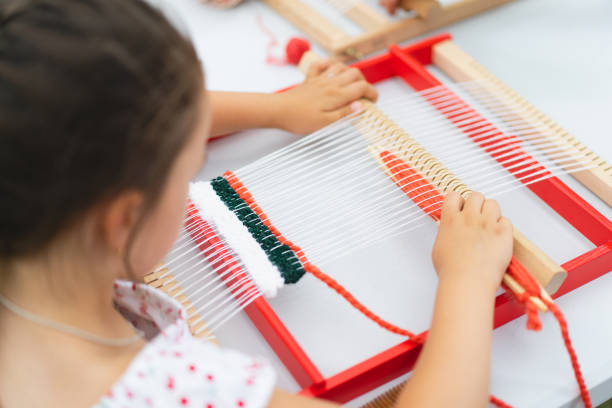 istock Girl weaving small rug with pattern at masterclass on weaving 1407990242