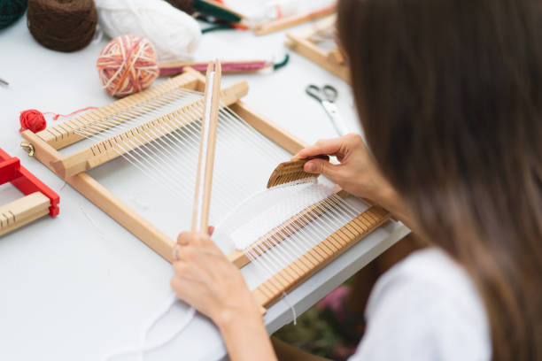 istock Girl weaving small rug with pattern at masterclass on weaving 1407990246