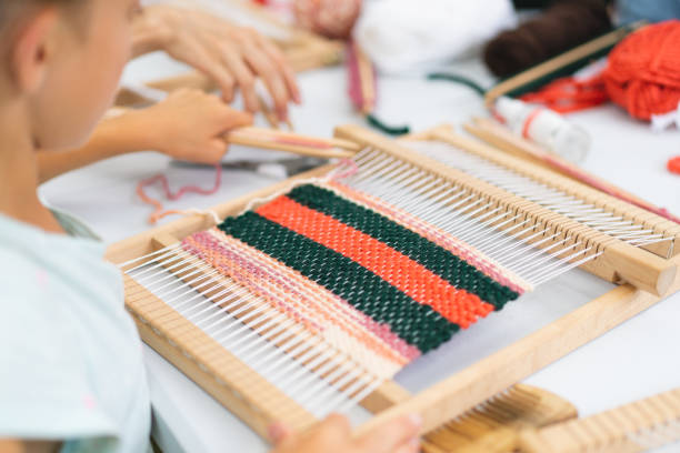 istock Girl weaving small rug with pattern at masterclass on weaving 1407990285
