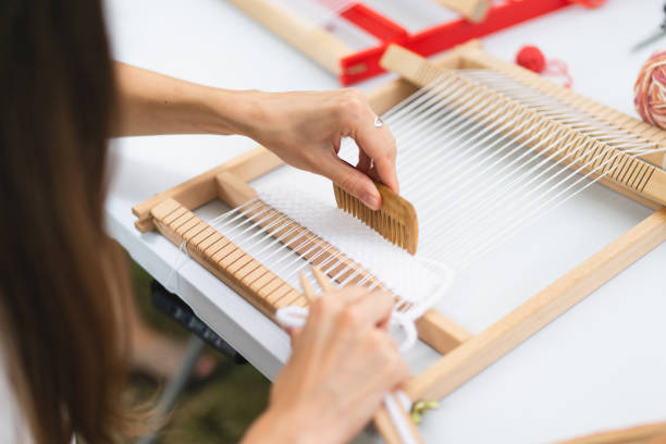 istock Girl weaving small rug with pattern at masterclass on weaving 1407990309