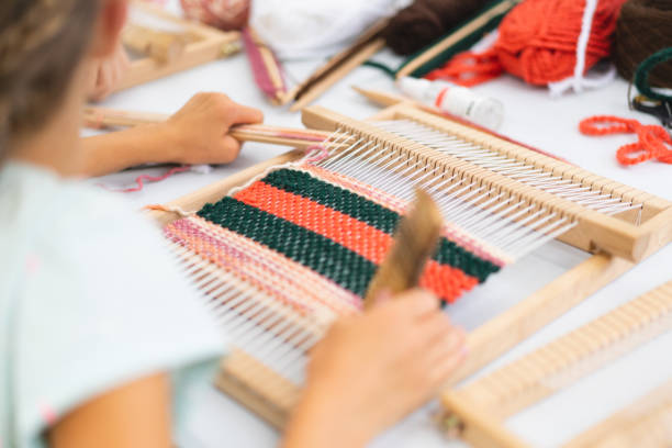 istock Girl weaving small rug with pattern at masterclass on weaving 1407990357
