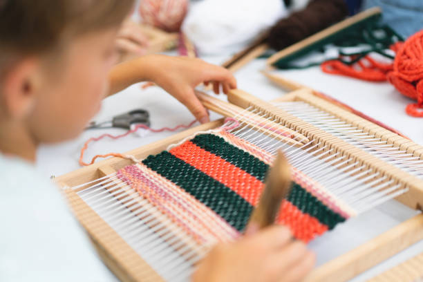 istock Girl weaving small rug with pattern at masterclass on weaving 1407990418