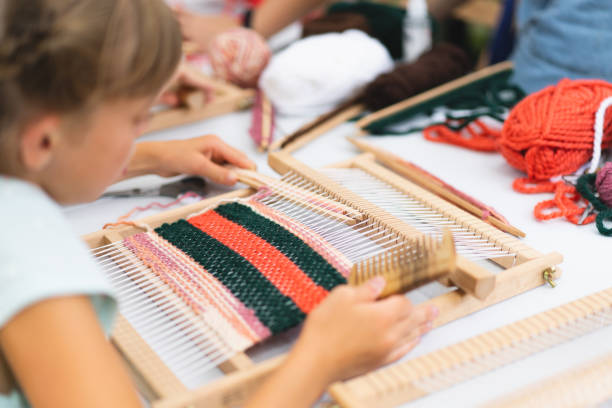 istock Girl weaving small rug with pattern at masterclass on weaving 1407990423