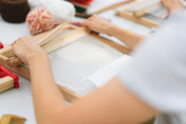 istock Girl weaving small rug with pattern at masterclass on weaving 1407990566