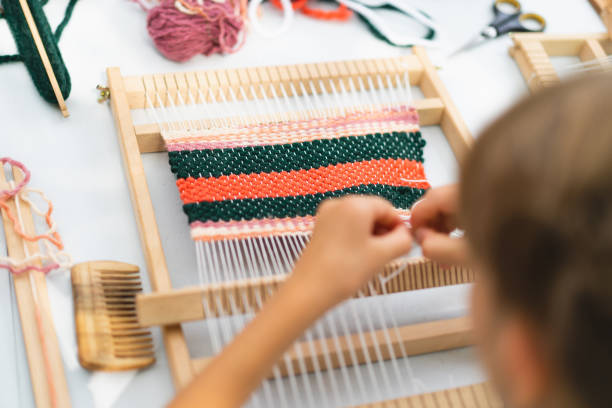 istock Girl weaving small rug with pattern at masterclass on weaving 1407990686