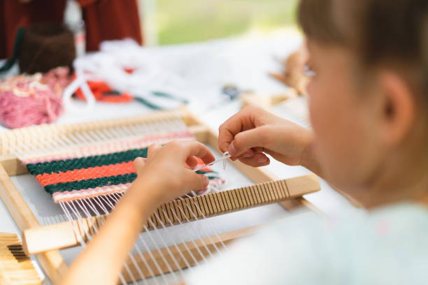 istock Girl weaving small rug with pattern at masterclass on weaving 1407990694