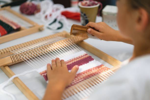 istock Girl weaving small rug with pattern at masterclass on weaving 1407990700