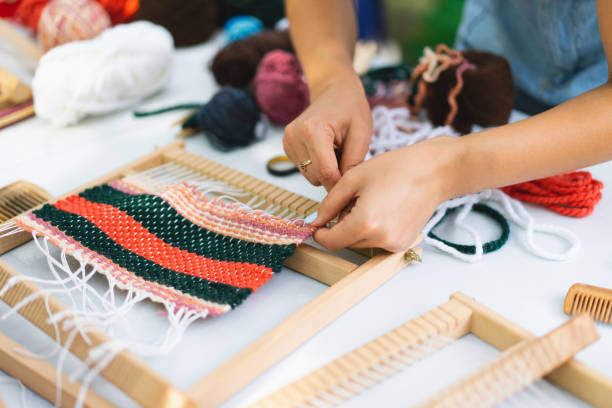 istock Girl weaving small rug with pattern at masterclass on weaving 1407990753