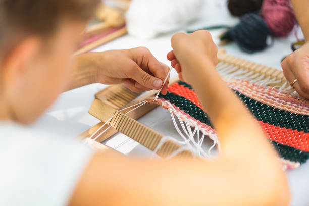 istock Girl weaving small rug with pattern at masterclass on weaving 1407990754