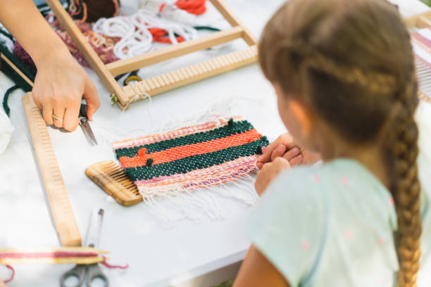 istock Girl weaving small rug with pattern at masterclass on weaving 1407991377