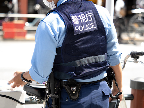 A police officer standing in the city. Taken in July 2022 in Taito-ku, Tokyo.