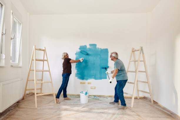 happy mature couple talking while painting their new apartment. - home addition home improvement paint decorating imagens e fotografias de stock