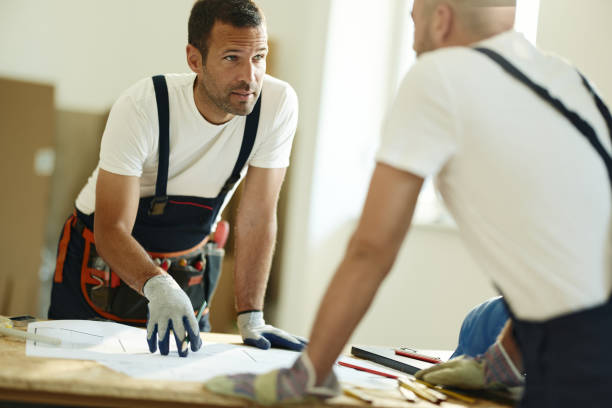 istock Manual worker talking to his colleague about blueprints on construction site. 1407993927