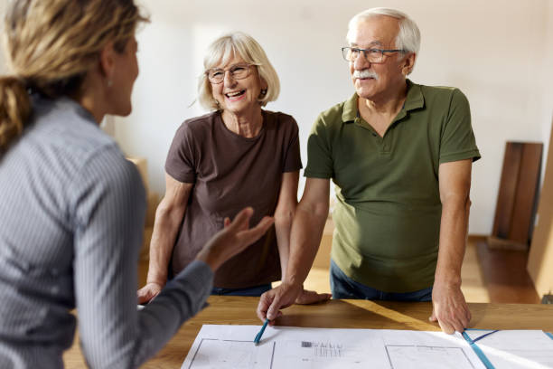Happy senior couple talking about blueprints with their architect.