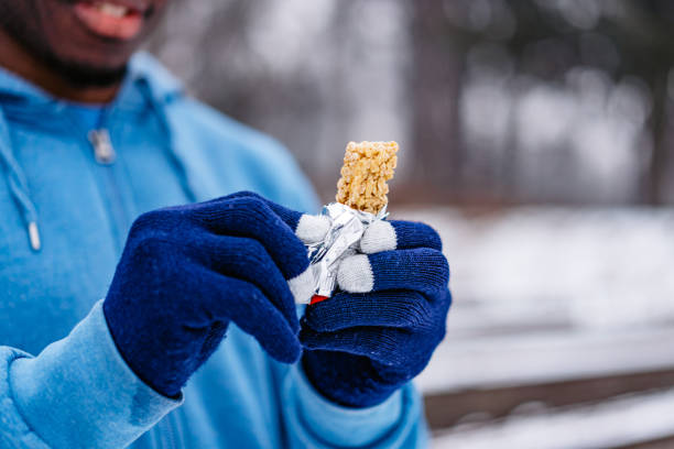 joven comiendo un bocadillo después de hacer ejercicio al aire libre - fresh snow audio fotografías e imágenes de stock