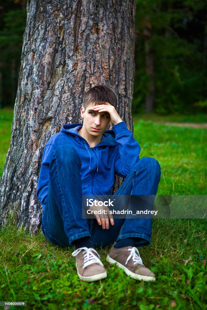 Sad Young Man Young Man sit under the Tree in the Park Men Stock Photo