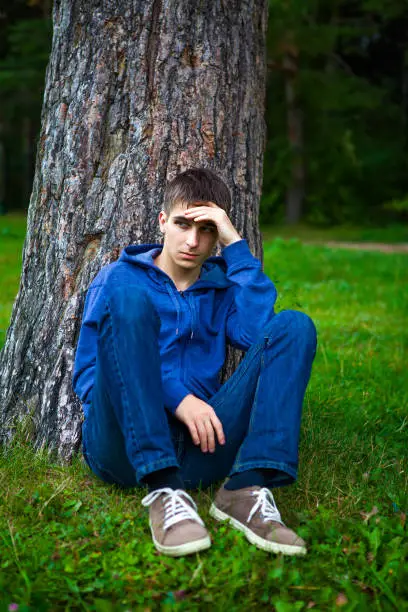 Young Man sit under the Tree in the Park