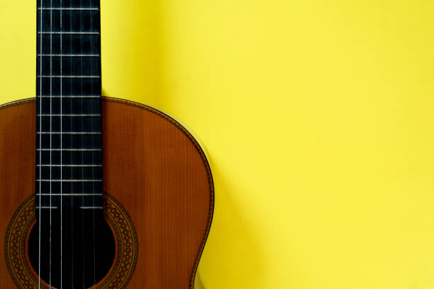 istock old classic guitar on yellow table background, music concept 1408000940