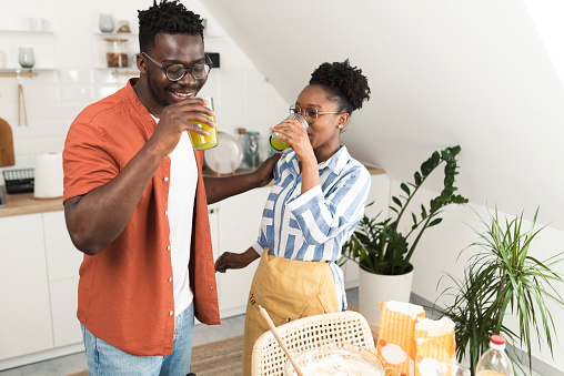 Young African American couple making homemade cookies and refreshing with juice at their kitchen