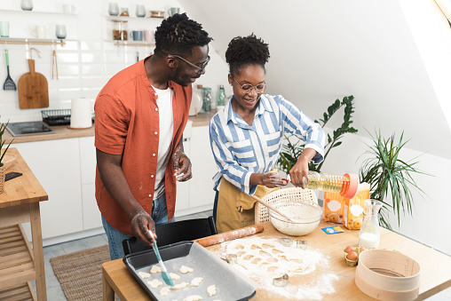 Young African American couple making homemade cookies at their kitchen