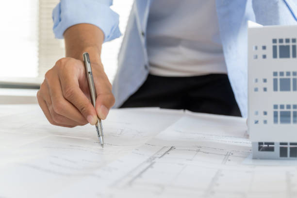 istock professional architect, engineer or interior hand reviewing blueprint with building model on workplace desk in office center at construction site, contractor, construction, engineering concept 1408003366