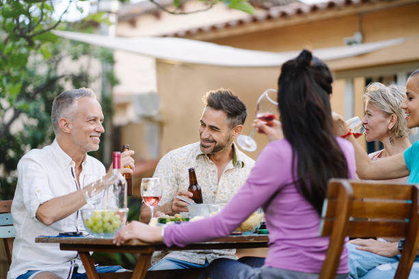 istock Mature friends enjoying conversation together at dinner during summer vacations 1408003847