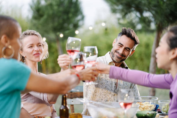 庭での夏の夕食中に、友人とワインのグラスを乾杯ハンサムなヒスパニック系の男性 - toast glass wine dinner ストックフォトと画像