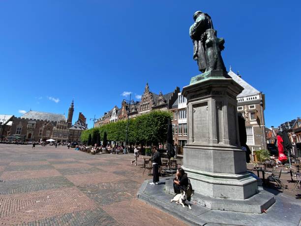 Haarlem, Netherlands, - June 28, 2022. People resting under statue on the square  in the city center of Haarlem.