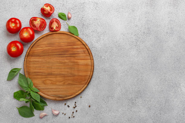 istock light culinary background with round wooden board, tomatoes and basil 1408008178