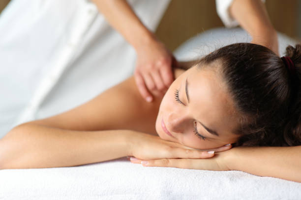 donna che si rilassa con massaggio del terapeuta nella spa - pampering massaging indoors adult foto e immagini stock