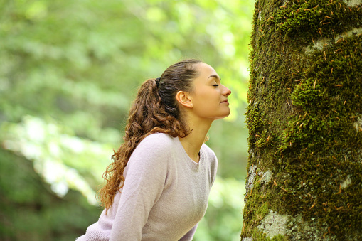 Woman smelling moss in a tree in a forest