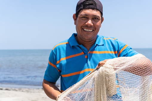 Smiling portrait of Latino fisherman with fishing net in hand
