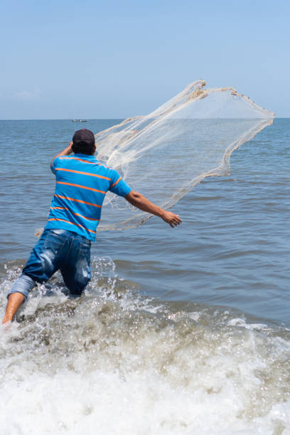 istock Fisher on the beach casting a fishing net 1408010304